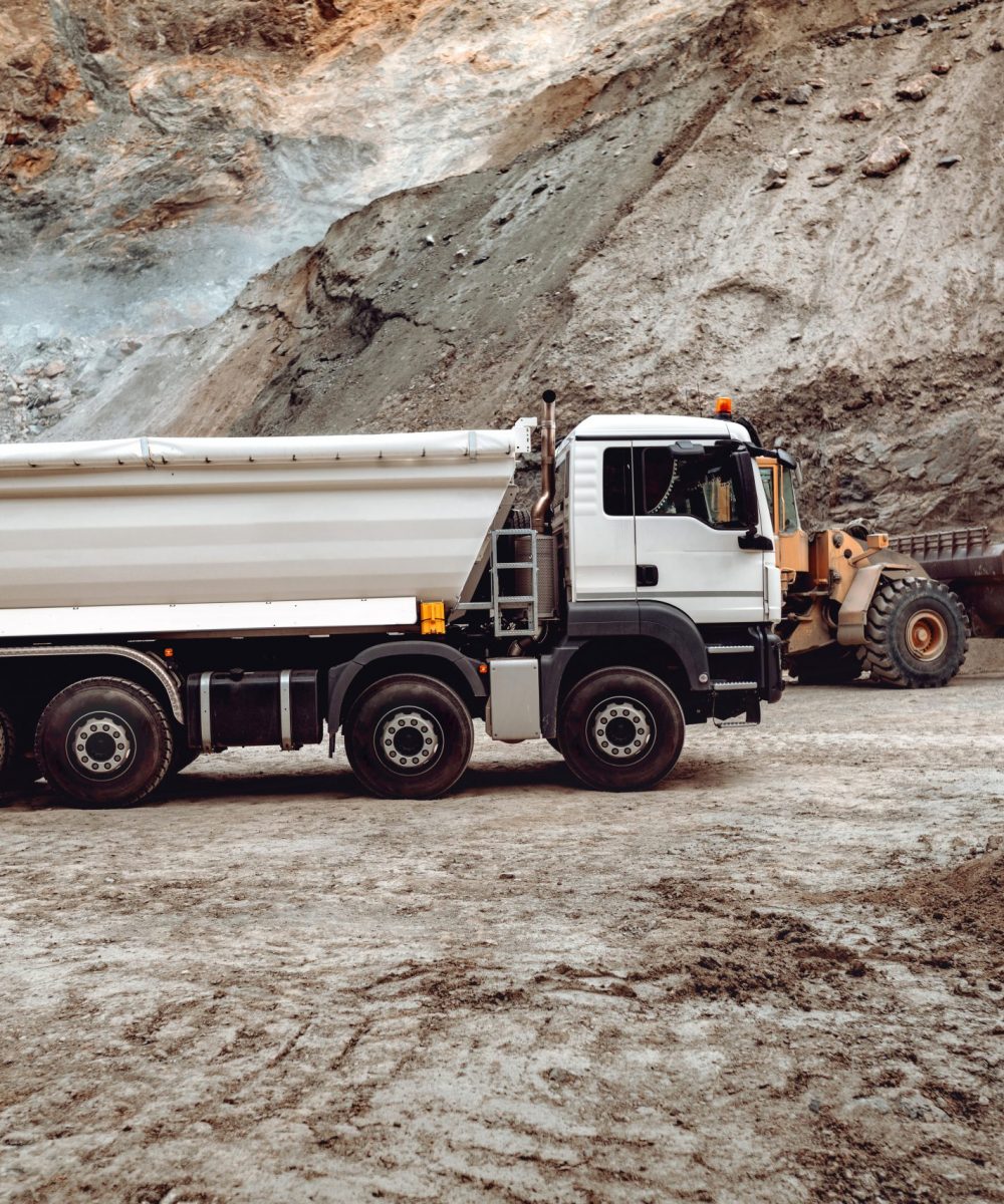 Industrial dumper trucks working on highway construction site, loading and unloading gravel and earth. heavy duty machinery activity and works