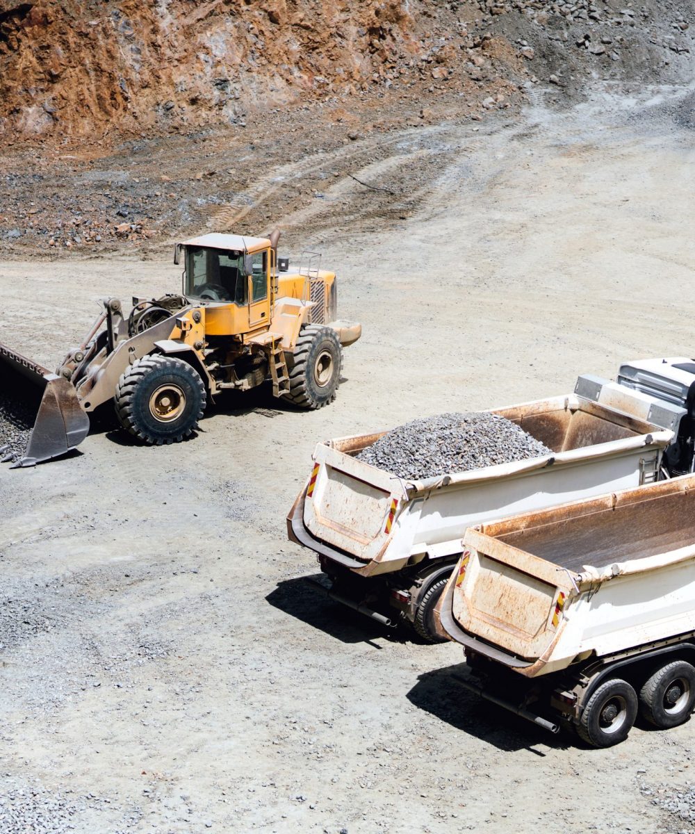 wheel loader working on site and loading dumper trucks. Heavy duty machinery working on construction site